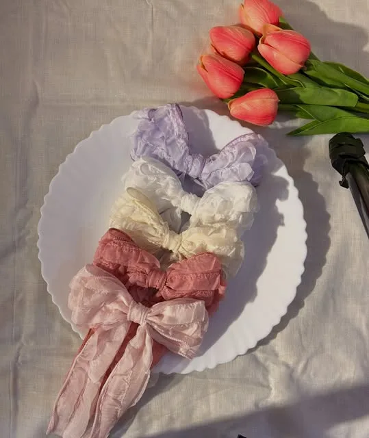 Lilac, white and pink lace bows on a white plate with tulips